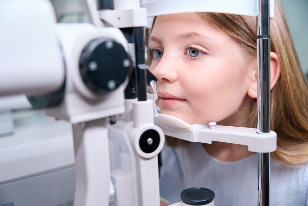 Young Girl Receiving Slit Lamp Eye Exam - Eye Exam Kingsport TN Close-up of a young girl sitting at an optometrist’s slit lamp machine during an eye examination - Eye Exam Kingsport TN.