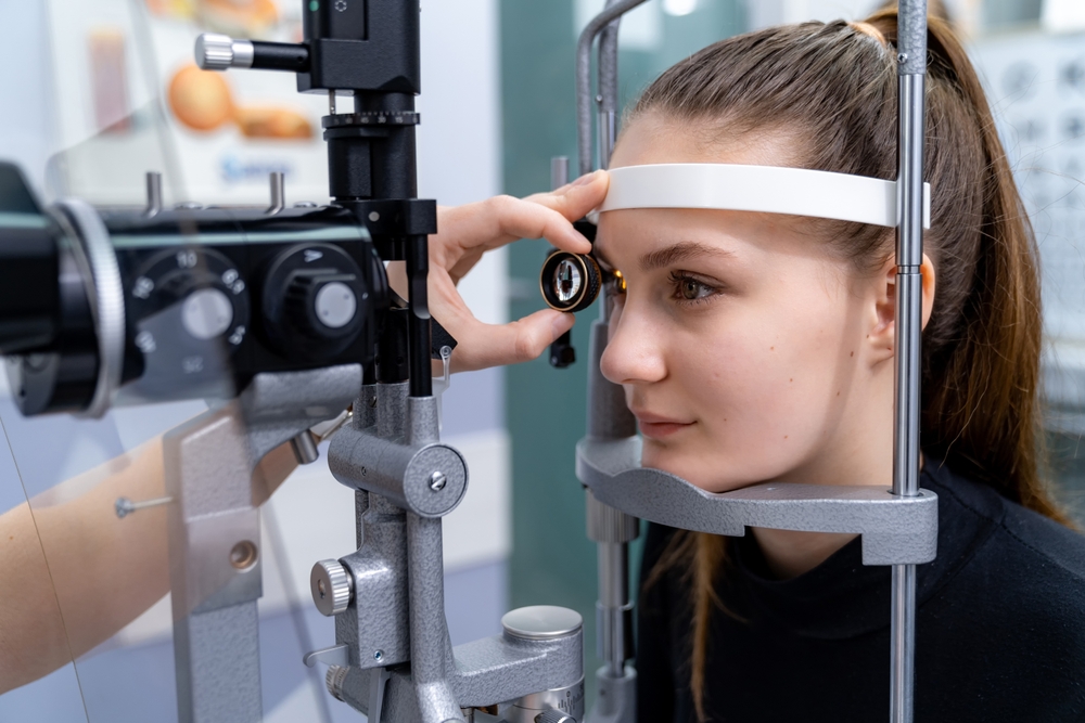 Woman Undergoing Slit Lamp Eye Examination - in Johnson City, TN Young woman sits in an optometrist’s chair during a slit lamp eye exam, focusing on the equipment - in Johnson City, TN.