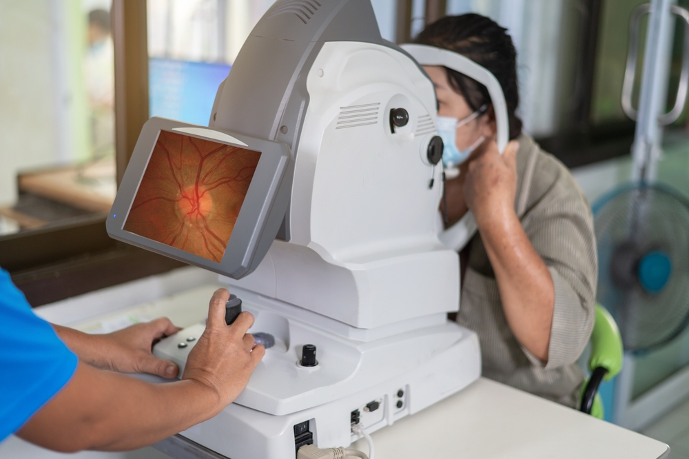 Retinal Imaging Eye Examination A woman undergoes a retinal imaging test, with the technician operating the machine and the eye scan image displayed on the screen.