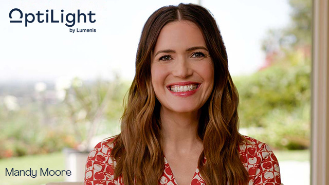 Mandy Moore Smiling in OptiLight Advertisement Actress Mandy Moore smiles in front of a bright background, featured in an OptiLight by Lumenis promotional image for eye health.